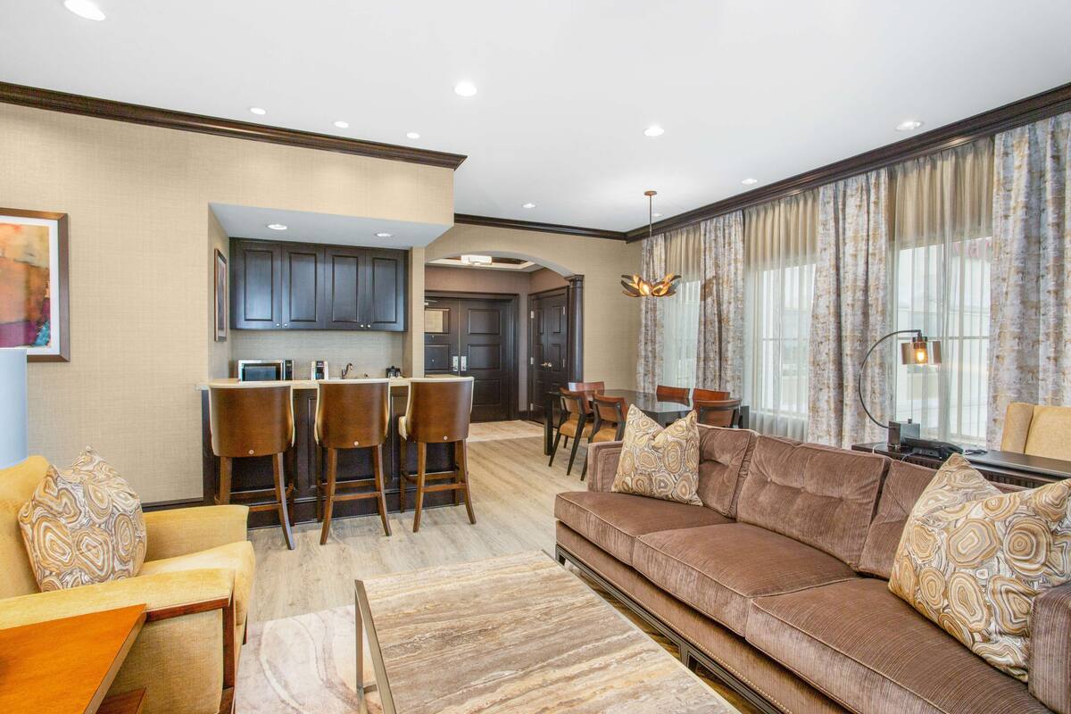 A spacious living area with a brown sofa, a coffee table, and a dining area with chairs and a table.