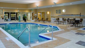 An indoor swimming pool with a lifeguard station, seating area, and a clock on the wall.