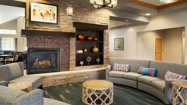 A cozy living area with a fireplace, comfortable seating, and decorative shelves.