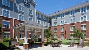 A hotel with a covered patio area, outdoor seating, and a barbecue grill.