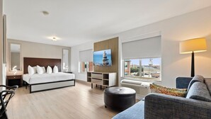 Una habitación de hotel moderna con cama, sofá, televisión, ventana y vista a la ciudad, además de una lámpara.