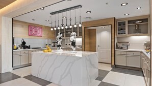 Una cocina moderna con una isla de mármol, iluminación colgante y armarios de madera.