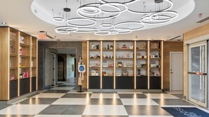 Un vestíbulo de hotel con piso a cuadros, una recepción y una pared de estanterías con diversos objetos.