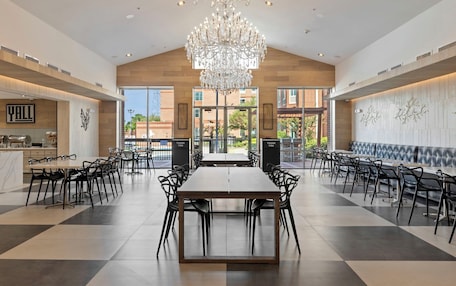 A spacious dining area with a long table and chairs, a chandelier, and a view of the outside.