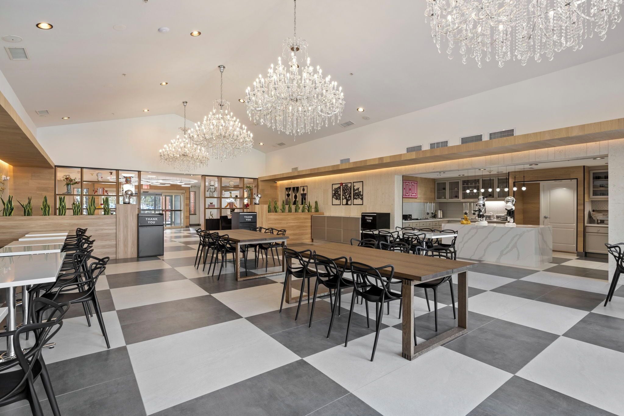 A spacious dining area with checkered flooring, multiple dining tables, and black chairs.