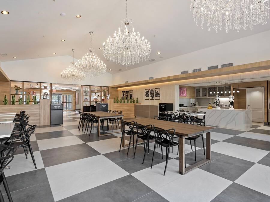 A spacious dining area with checkered flooring, multiple dining tables, and black chairs.