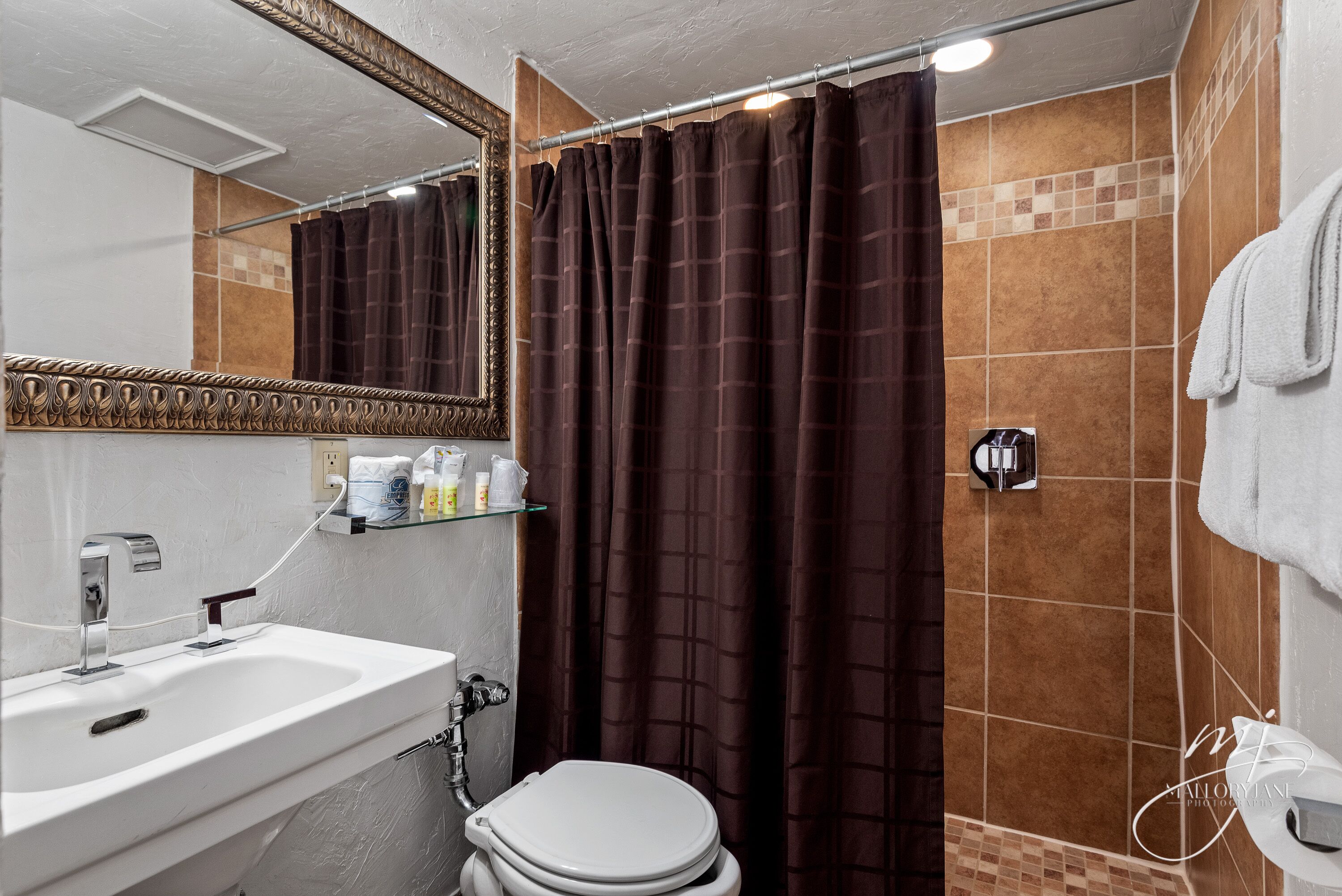 Une salle de bain avec un lavabo blanc, un miroir, un rideau de douche et un porte-serviettes.