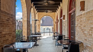 An outdoor cafe with brick walls, arched doorways, and tables and chairs arranged for dining. - Hotel Seville (Harrison)