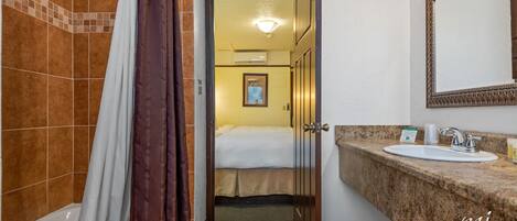 A hotel bathroom with a bathtub, shower curtain, sink, and mirror.