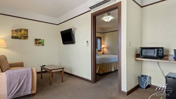 A hotel room with a bed, a TV, a microwave, a small table, and a couch.