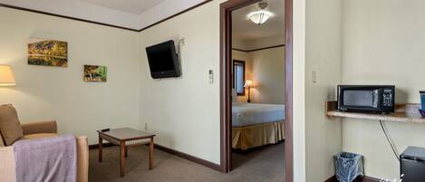 A hotel room with a bed, a TV, a microwave, a small table, and a couch.