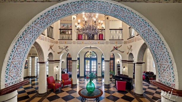 A lobby with a checkered floor, a chandelier, red chairs, and a green vase on a table. - Hotel Seville (Harrison)
