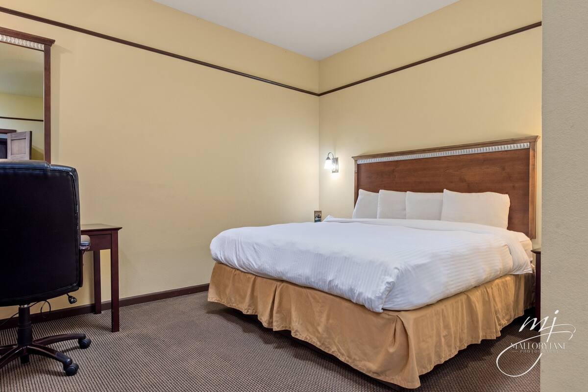 A hotel room with a large bed, a desk, and a chair.