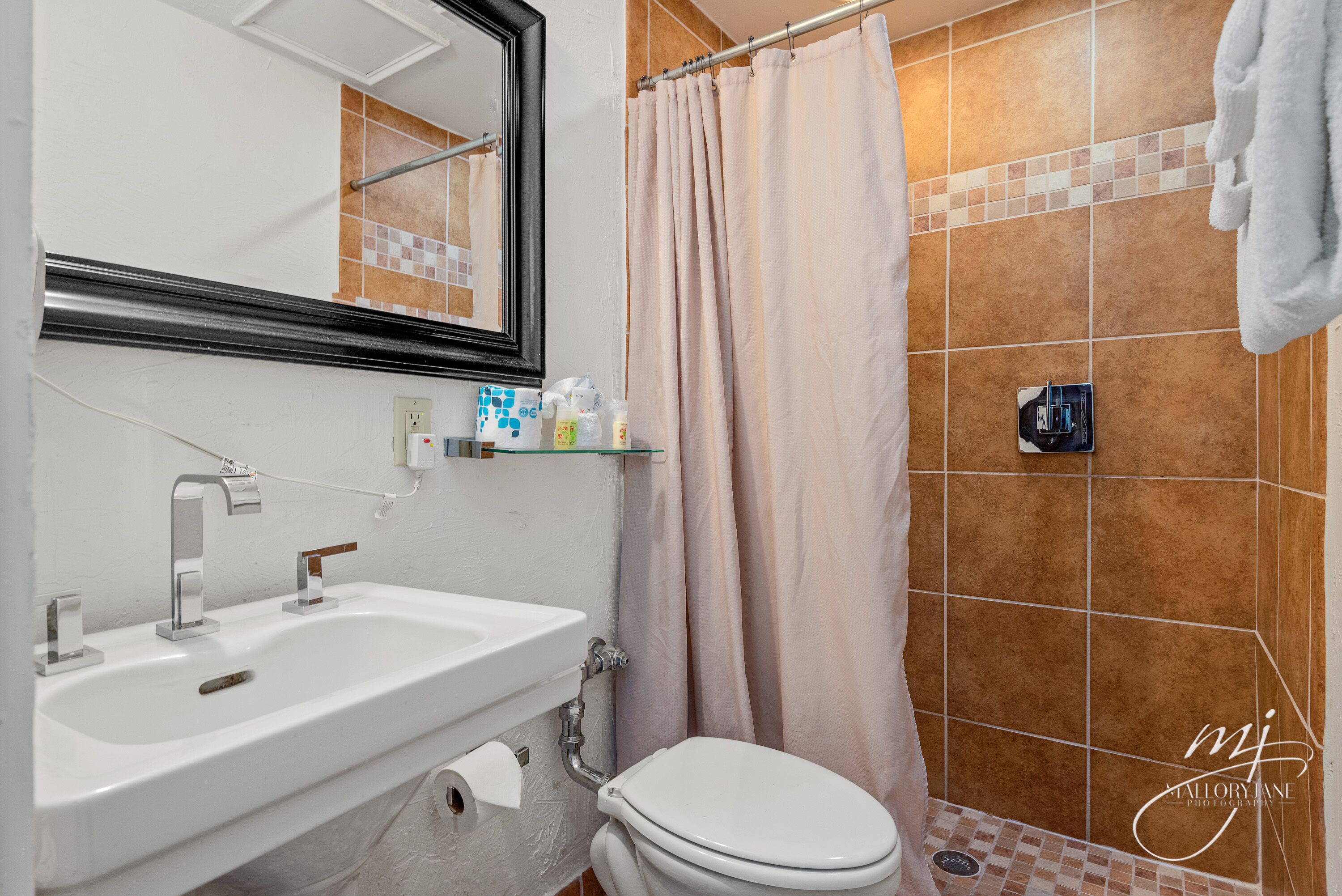 Un baño con lavamanos blanco, inodoro y cortina de ducha.
