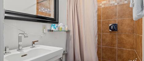 Un baño con lavamanos blanco, inodoro y cortina de ducha.