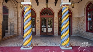 A building entrance with brick walls, arched doorways, and a tiled floor. - Hotel Seville (Harrison)