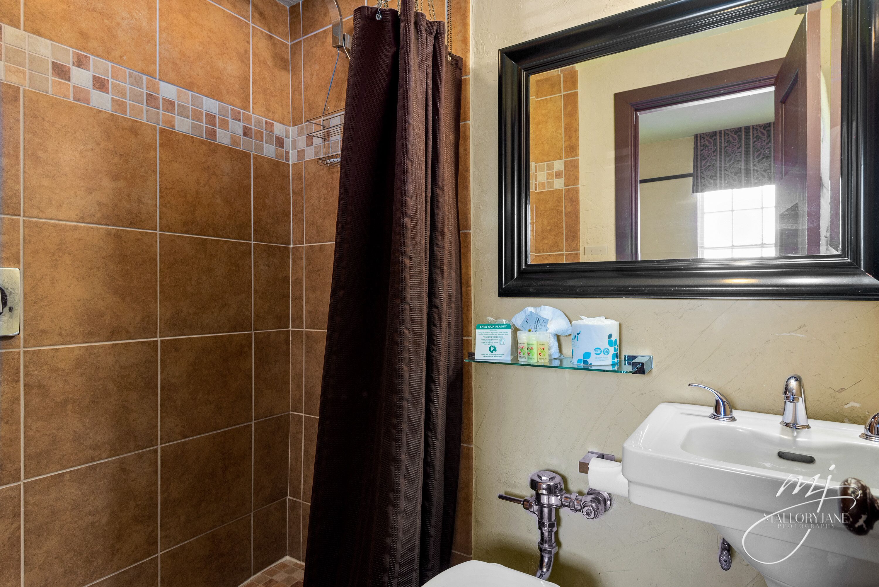 Un baño con ducha, lavamanos y espejo.