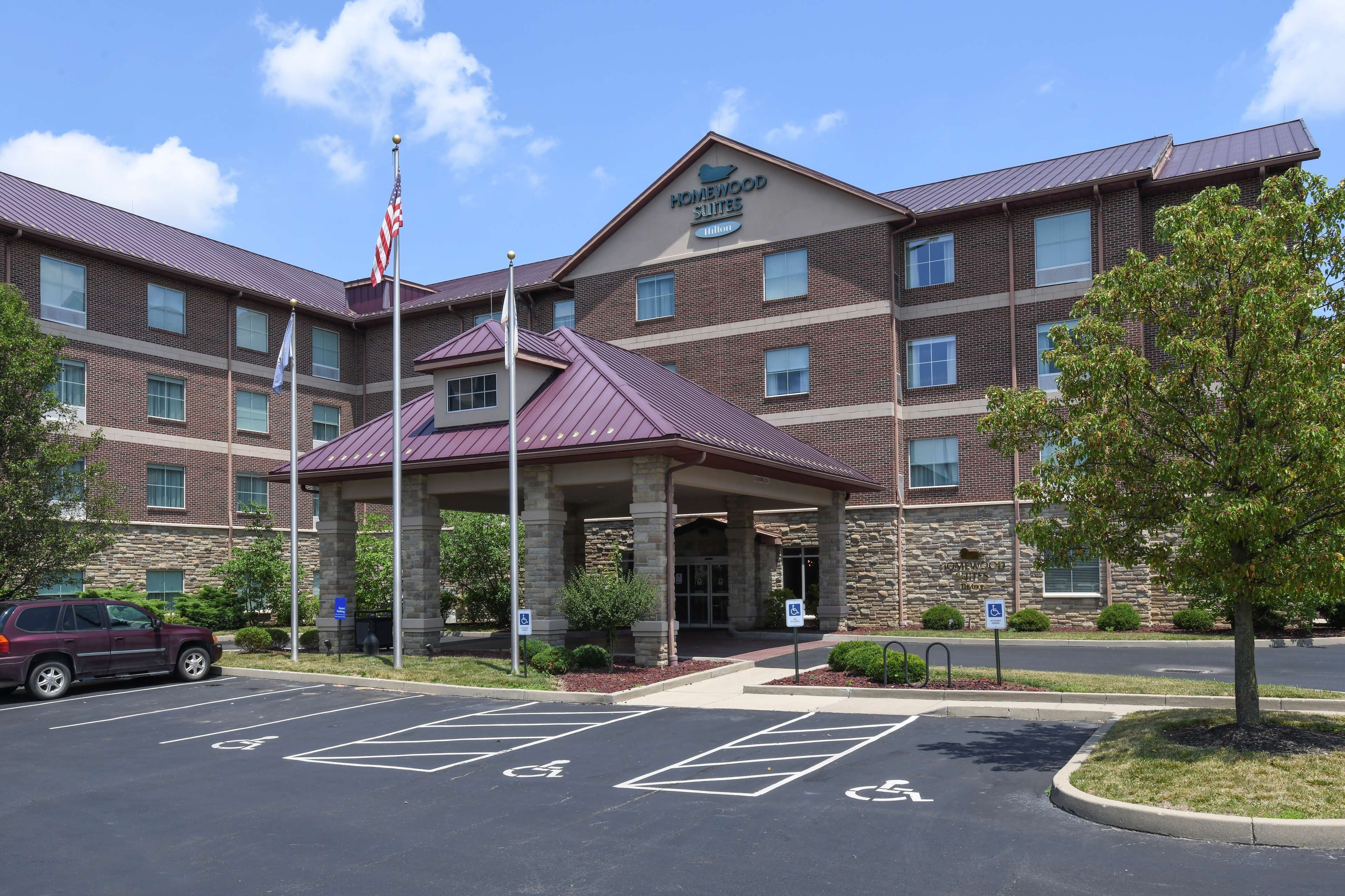 A hotel with a brick facade, a covered entrance, and a parking lot with handicapped spaces.