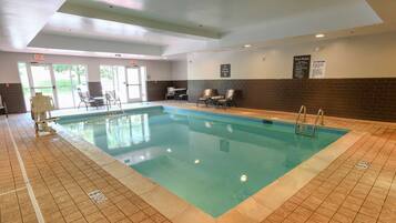 An indoor swimming pool with clear water, tiled floor, and a lifeguard chair.
