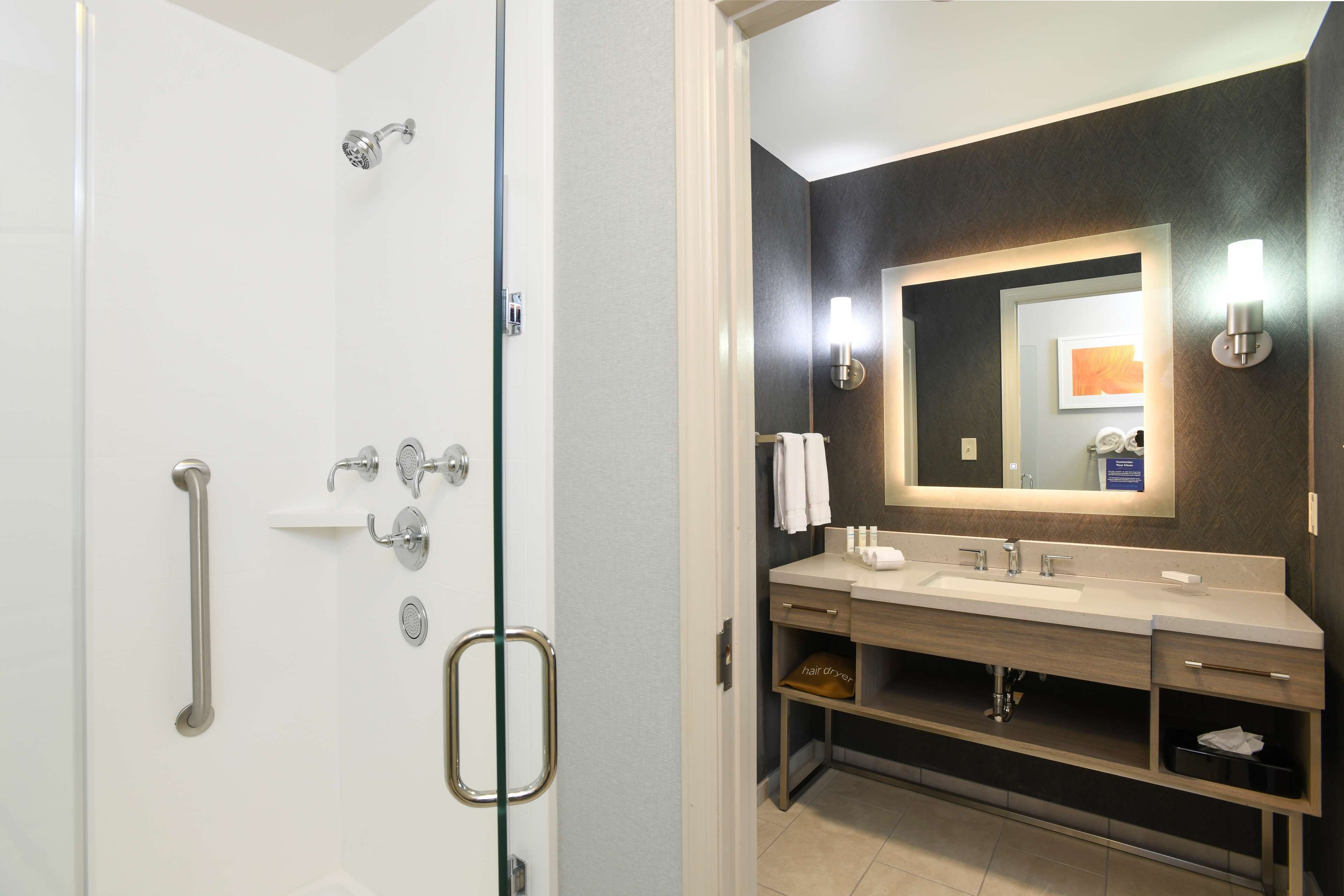 A modern bathroom with a walk-in shower, a vanity with a mirror, and a towel rack.