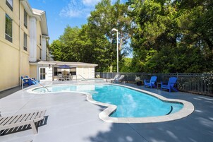 Una piscina al aire libre, sillones reclinables de piscina