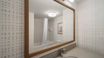 A bathroom with a large mirror, a shower, a toilet, and a sink.