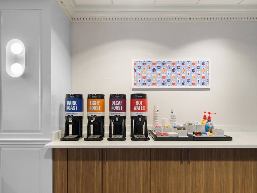 A coffee station with four dispensers labeled DARK ROAST, LIGHT ROAST, DECAF ROAST, and HOT WATER.