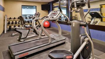 Een sportschool met loopbanden, elliptische trainers en gewichten.