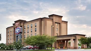 Classic hotel with a central entrance and two wings, surrounded by a well-manicured lawn and parking area.