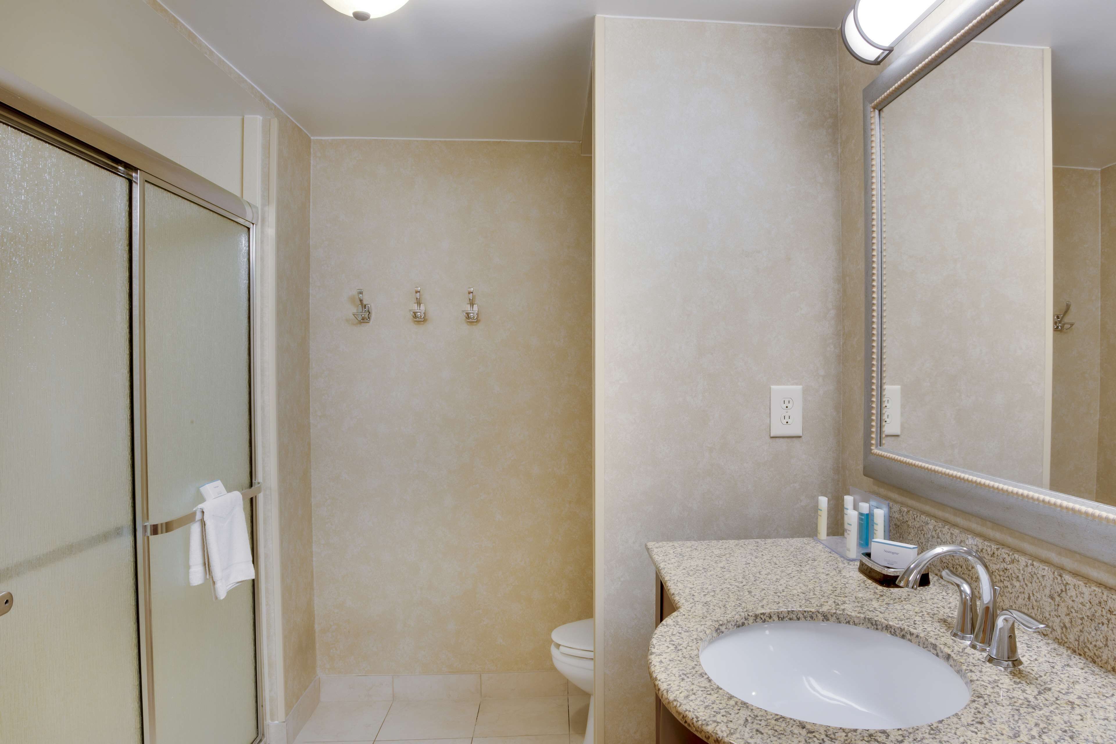 Une salle de bain avec une porte de douche en verre, un lavabo avec un grand miroir et des toilettes.