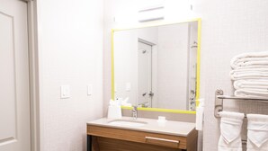 A bathroom with a sink, mirror, towel rack, and a door.