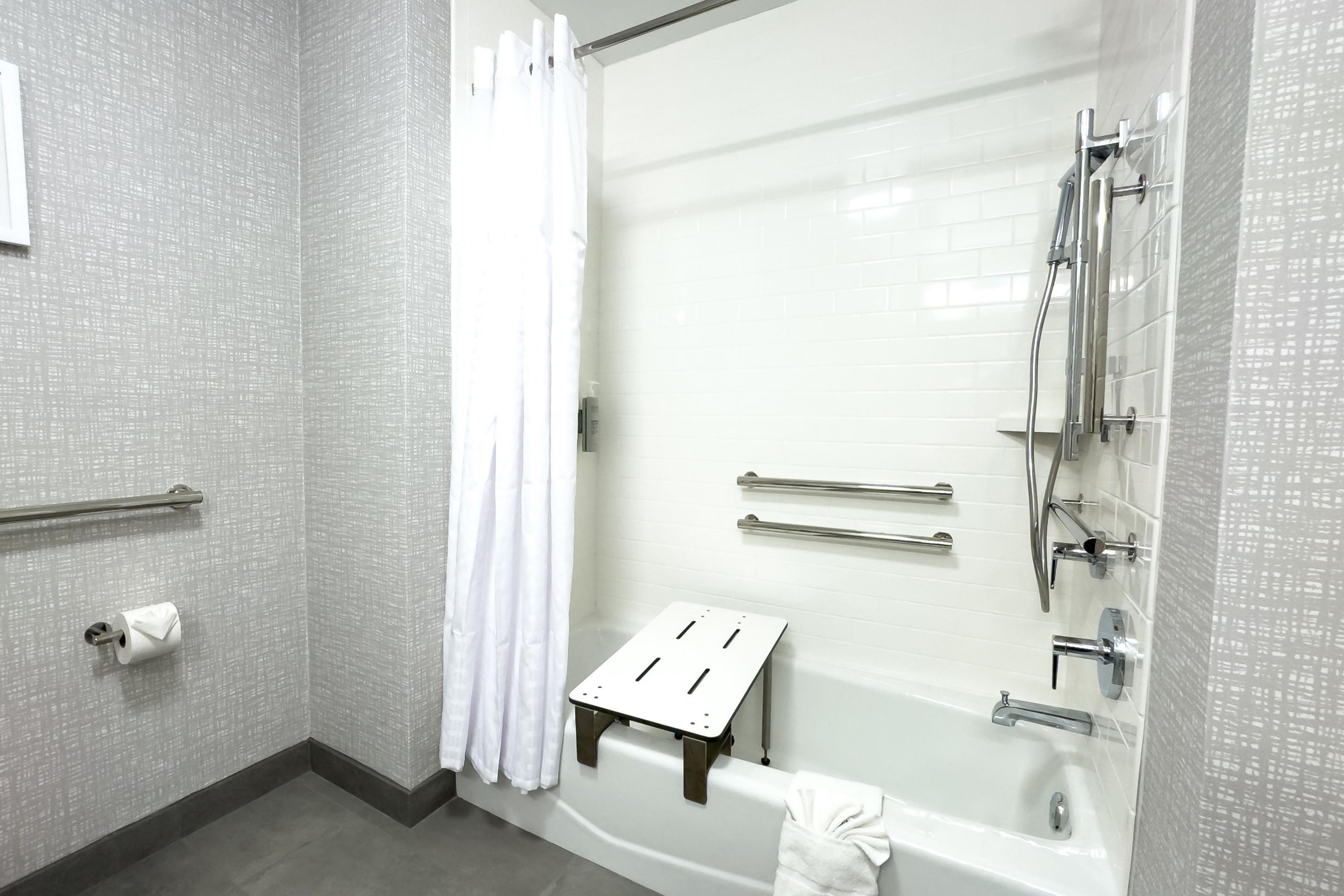 Un baño moderno con bañera, ducha y barras de apoyo.