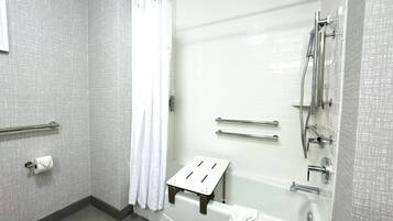 Un baño moderno con bañera, ducha y barras de apoyo.