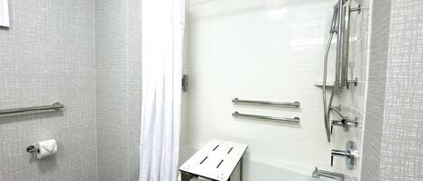 Un baño moderno con bañera, ducha y barras de apoyo.