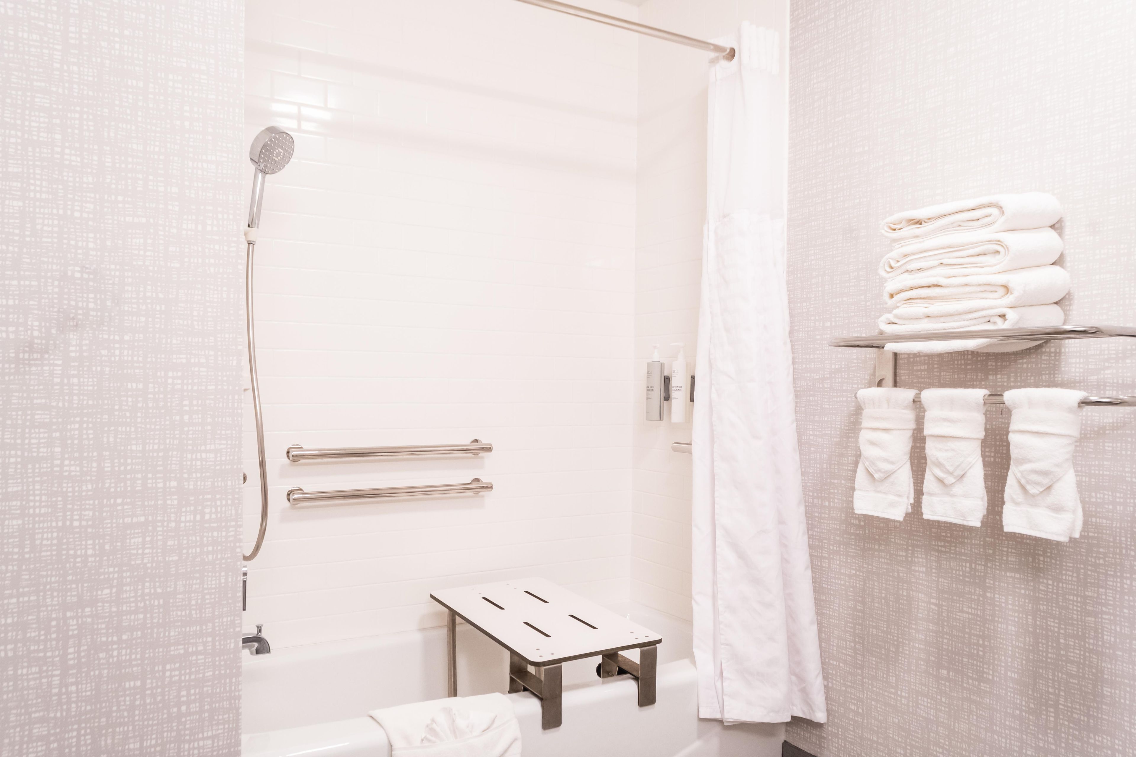 A modern bathroom with a shower, a toilet, and a towel rack.
