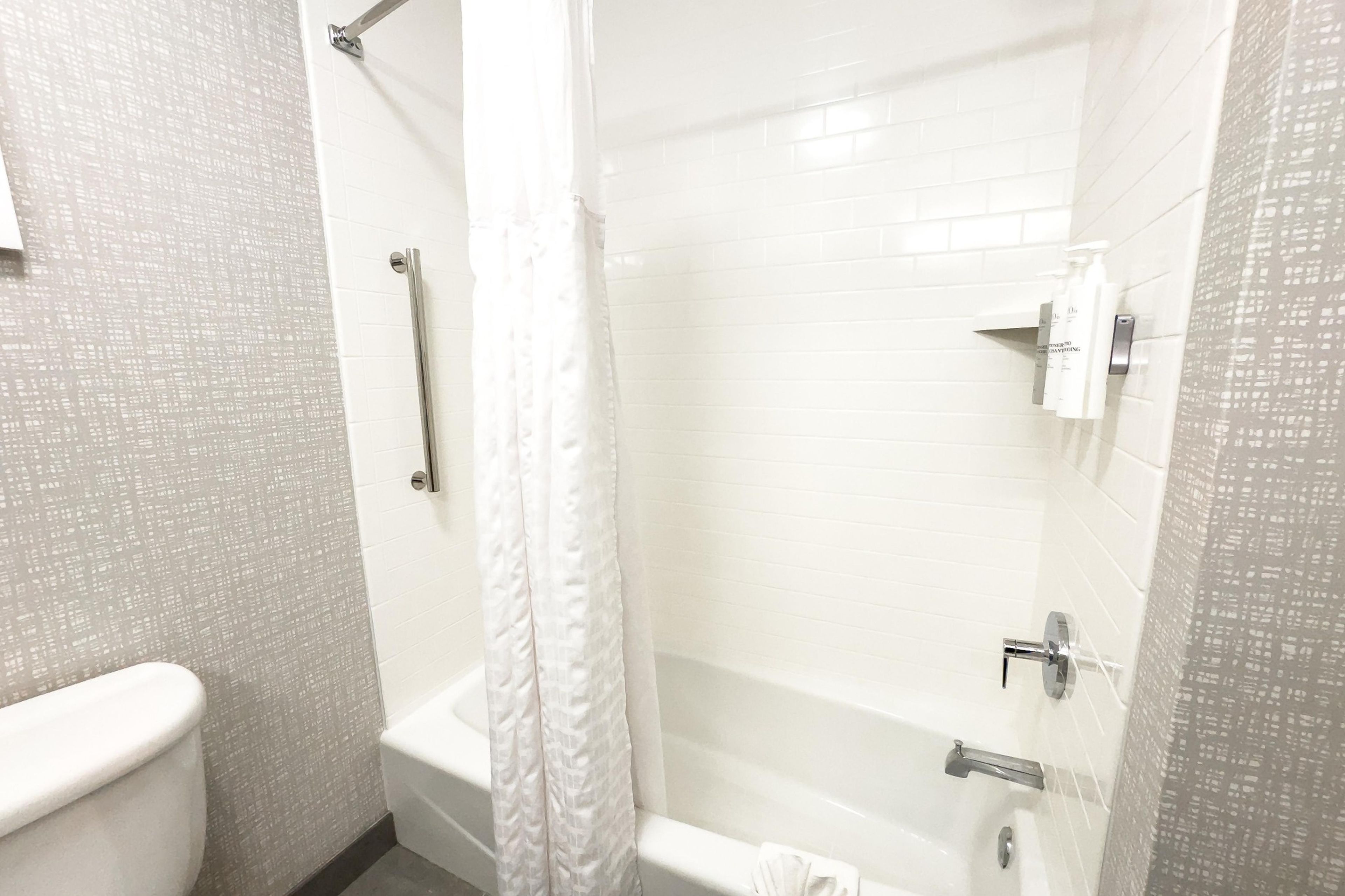 A bathroom with a shower, toilet, and a towel rack.