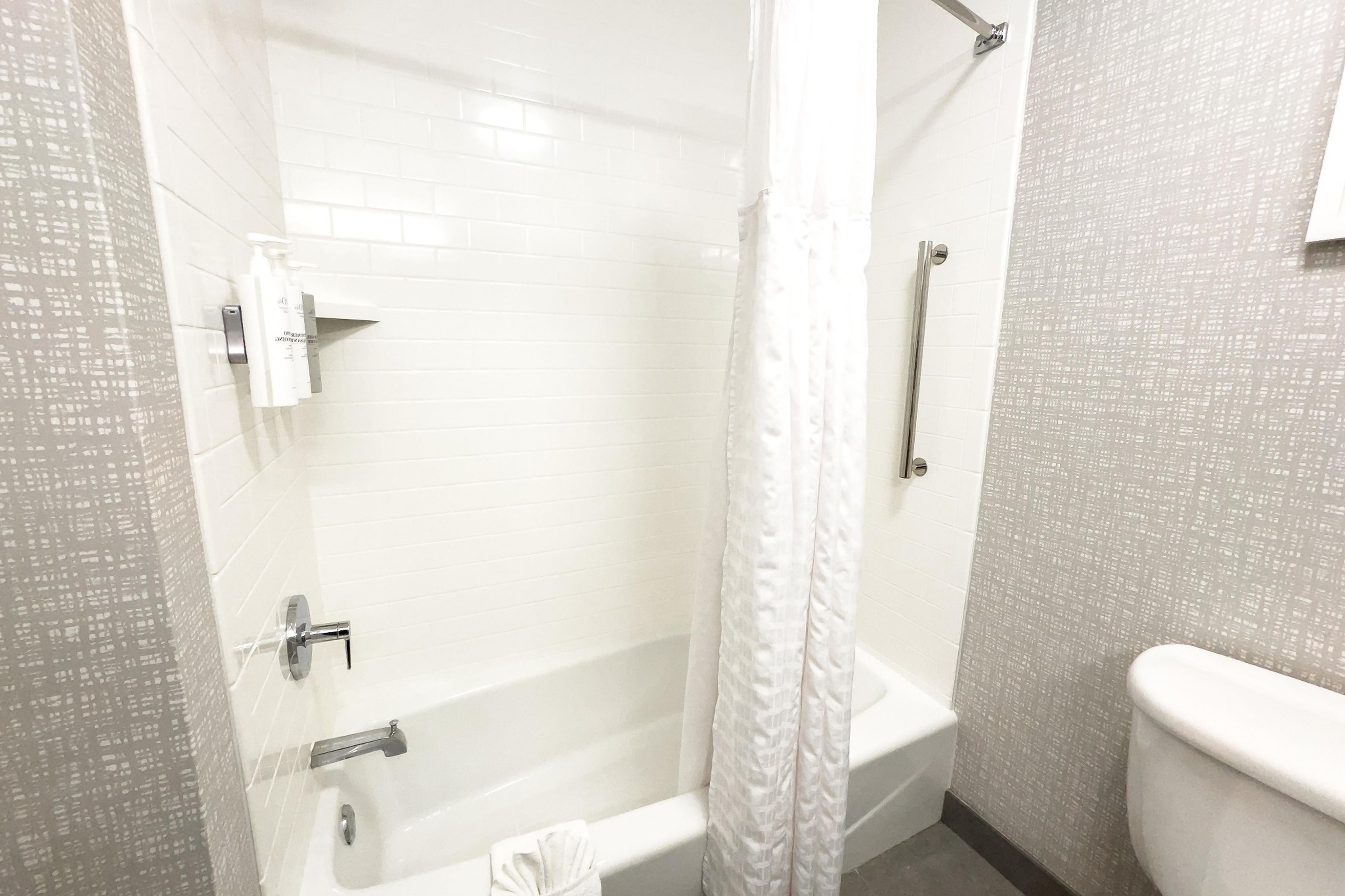 Un baño con bañera, cortina de ducha, inodoro y secador de manos.