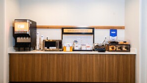 A breakfast bar with a coffee machine, microwave, and bakery display.