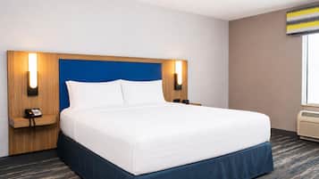 Una habitación de hotel con una cama grande, un teléfono en la mesita de noche y una lámpara de pared.