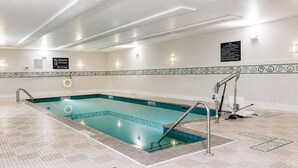 A swimming pool with a tiled deck, a lifeguard chair, and a no diving sign.