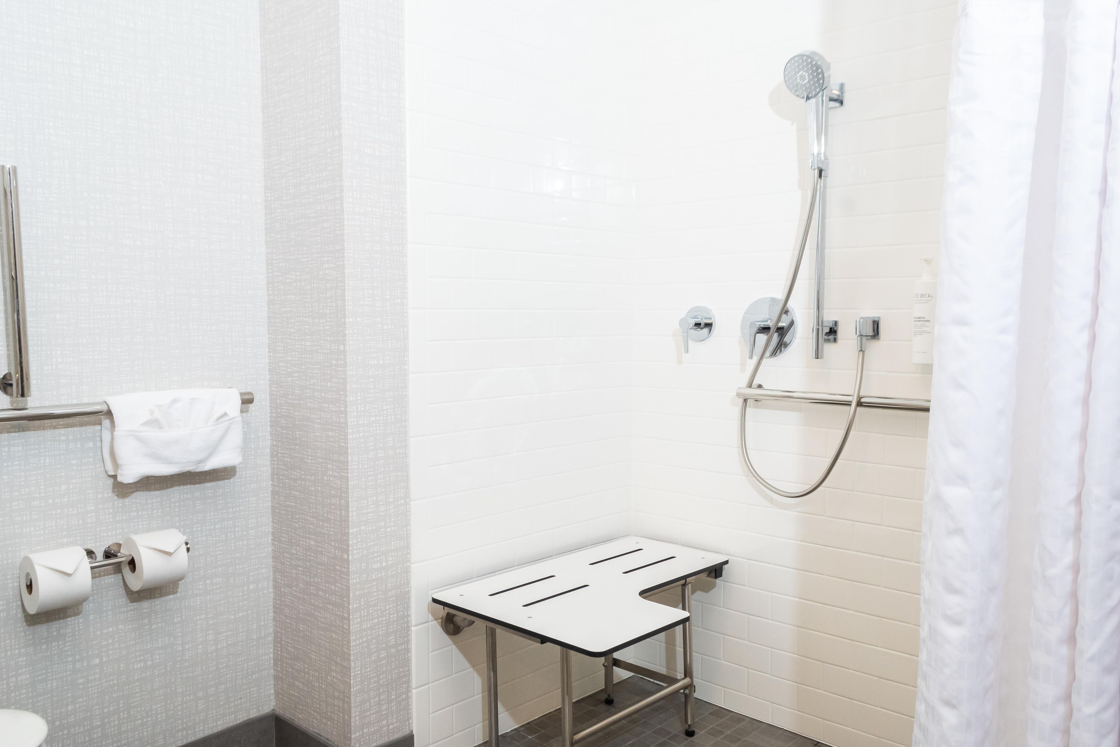 A modern bathroom with a shower, toilet, and towel rack.
