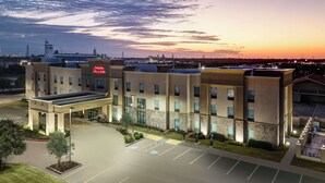 A hotel with a flat roof, a parking lot, and a large building with a sign that reads "Hampton Inn & Suites". - Hampton Inn & Suites Lake Jackson-Clute (Clute)