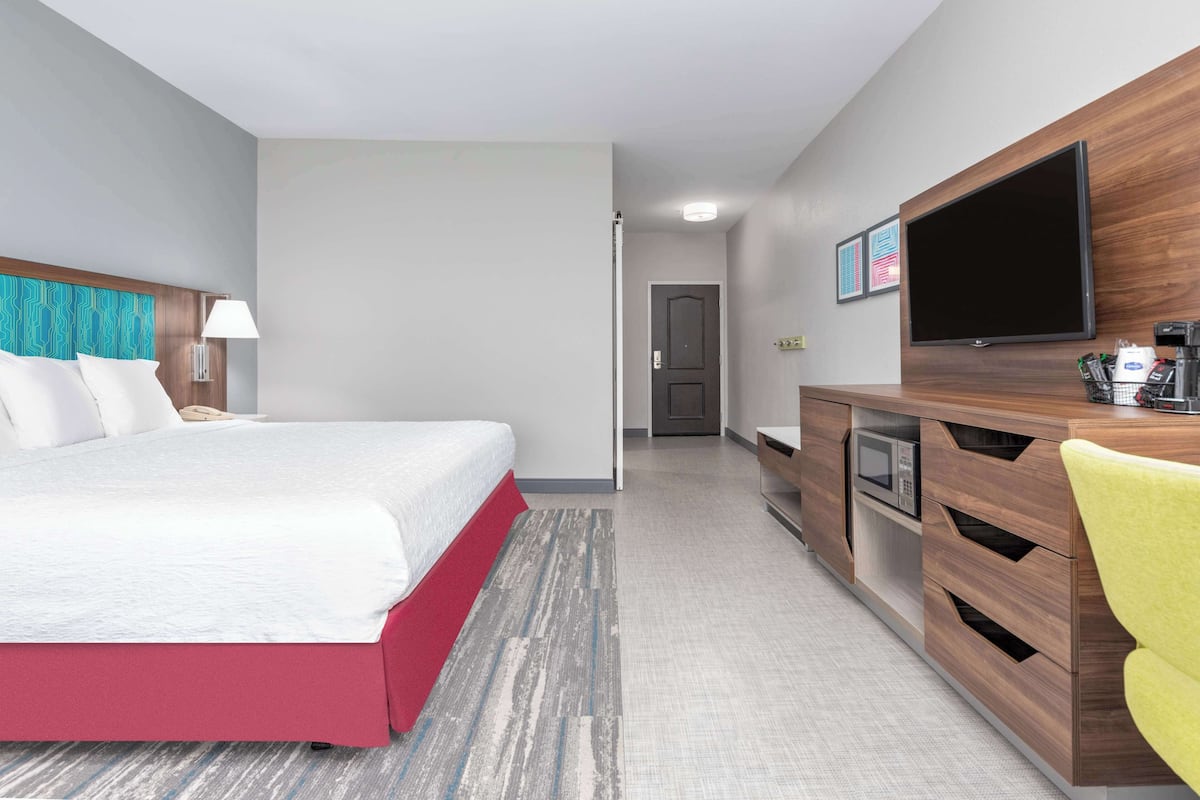 A hotel room with a bed, a desk, a television, and a microwave.
