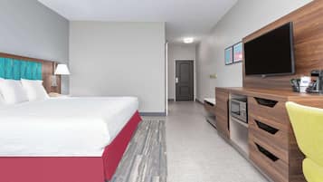 A hotel room with a bed, a desk, a television, and a microwave.