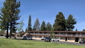 A motel with a two-story structure, parking lot, and surrounding trees. - Beverly Lodge (South Lake Tahoe)