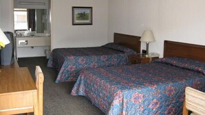 Une chambre d’hôtel avec deux lits, un bureau, une chaise, un miroir et un tableau au mur.