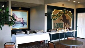 Un hall d’hôtel avec une table dressée pour le dîner, un tableau représentant un cheval et une enseigne murale indiquant « Walking Horse Lodge ».
