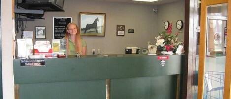 A reception desk with a green counter, a clock, and a framed picture on the wall.