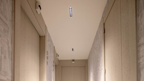 Un pasillo estrecho con suelo de baldosas claras y puertas de madera a ambos lados.
