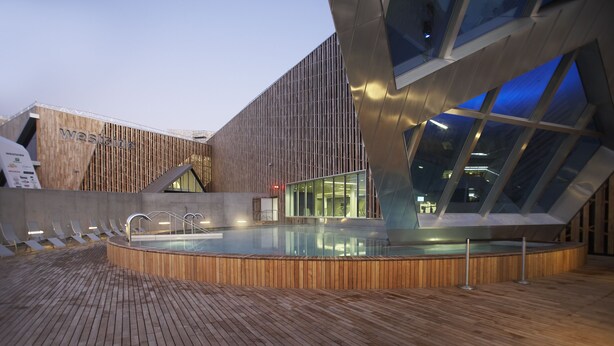 A modern building with a wooden deck and a pool area. - Holiday Inn BERN-WESTSIDE by IHG (Bern)